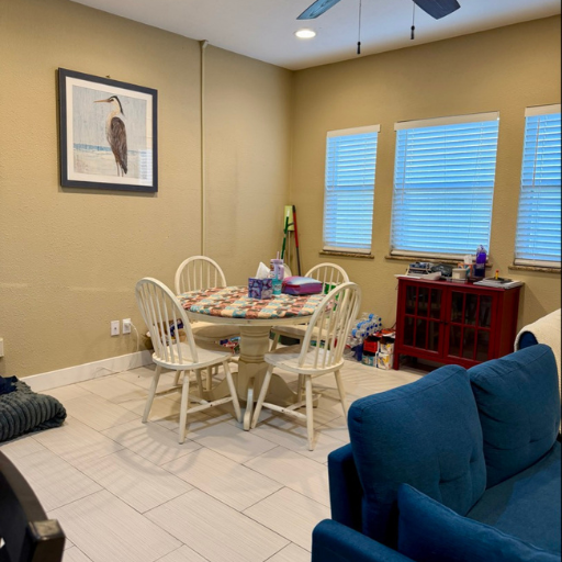 Dining area with round table, coastal heron art and bright windows at Cottage at Delasandri Kemah