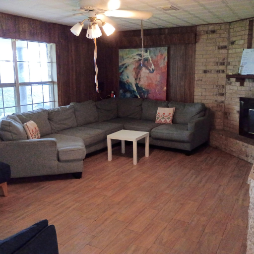 Communal living room with sectional sofa, brick fireplace and horse art at Sue Drive
